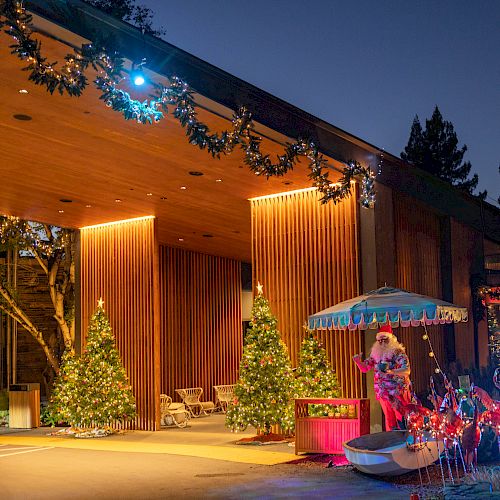 The image shows a festive outdoor scene with holiday decorations, including Christmas trees, garlands, and illuminated figures under an awning.